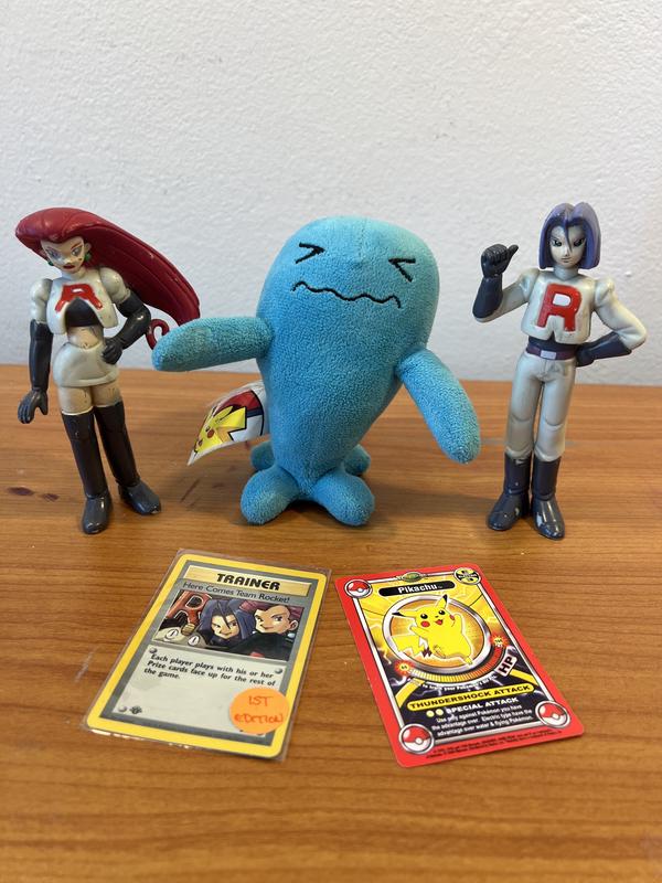 Shannon's treasured Pokémon items include figures of Jessie and James, a Here Comes Team Rocket! trading card, a ThinkChip Pikachu card, and a Wobbuffet plush toy