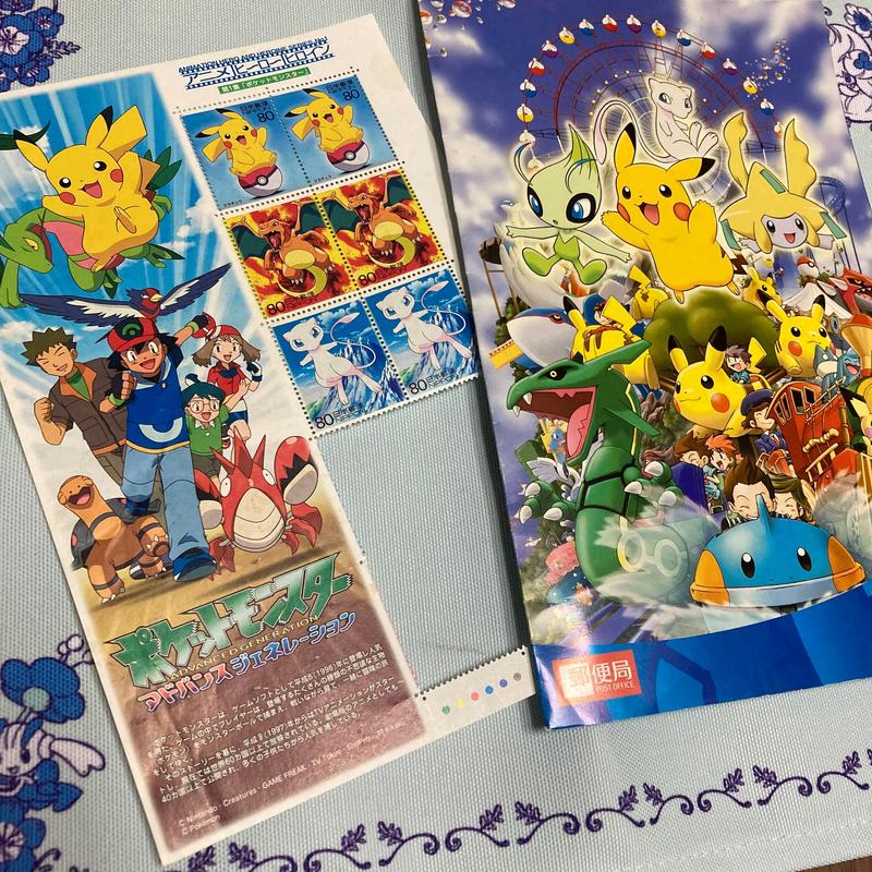 A photograph of Shiori’s stamps, featuring Pikachu, Charzard, and Mew. There is also an advertisement for the Pokémon Advanced Generation anime