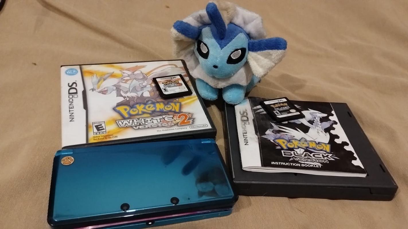 Lady Vulpix's original copies of Pokémon Black, and Pokémon White 2, alongside her Aqua Blue Nintendo 3DS, and her Vaporeon plushie
